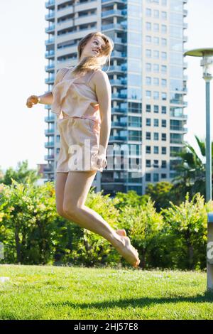 Smiling female is playfully jumping in the park Stock Photo
