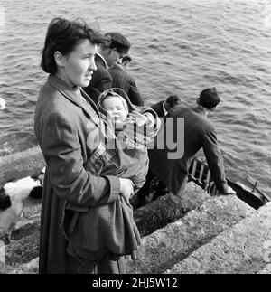 The last twenty three residents of Inishark Island (sometimes called Shark Island), off the coast of County Galway, Ireland, are pictured evacuating the Island. The residents have lost their battle with the winds. After being cut off from the mainland for weeks, sometimes months on end, the six families have left for the mainland to live in houses provided by the Irish government. 21st October 1960. Stock Photo