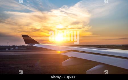 airplane wing at sunset. travel, air travel. Flying and traveling, view from airplane window on the wing on sunset time. Looking over aircraft wing in Stock Photo