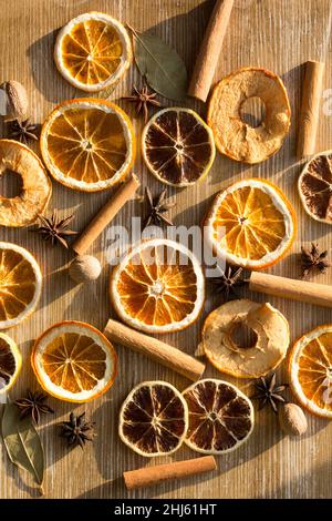 Top view of dry pieces of lemon, orange and apples, cinnamon sticks, bay leaves, nutmegs and star anise as background as ingredients for mulled wine a Stock Photo