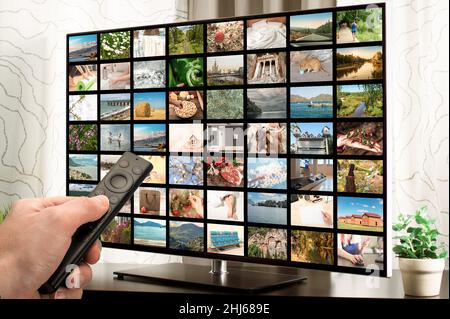 Male hand holding TV remote control. Multimedia streaming concept. VoD content provider concept. Video service with internet streaming multimedia, thu Stock Photo