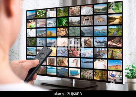 Man choosing what to watch on TV at home. Video on demand or VOD abstract concept. Man choosing film to watch with remote. Changing video content with Stock Photo