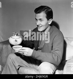 American singer Pat Boone in the UK for a series of television and variety engagements. 22 year old Pat is a father of three children. He has sold 14,000,000 records in two years. He is still studying for his BA and works about two weeks a month singing and two weeks at college. Pictured having a cup of tea. 25th December 1956. Stock Photo