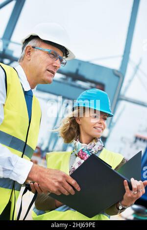 Slight confusion. Two engineers discussing planning on a site while looking away. Stock Photo