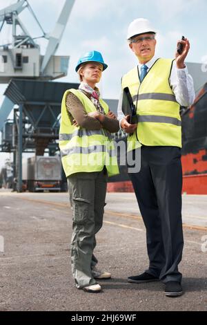 Effective communication among co-workers is vital. Two engineers discussing planning on a site while in the shipyard. Stock Photo