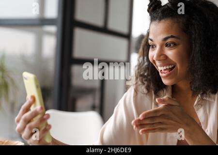 Young happy african american woman holding smart phone making a vlog from home Stock Photo