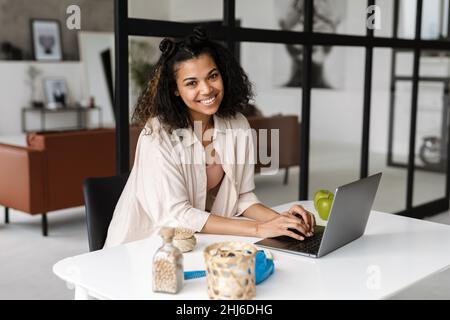 Black young woman smiling and working with laptop at home Stock Photo