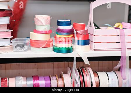 gift wrapping ribbons on a counter in a flower shop. various colors of ribbons for presents. gifts for holidays.  Stock Photo