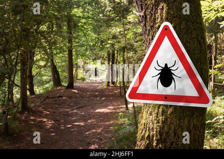 Infected ticks warning sign in a forest. Risk of tick-borne and lyme disease. Stock Photo