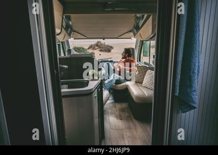 Adult man sitting inside van camper motorhome. Tourist of alternaive people lifestyle. Travel and enjoying freedom. Holiday vacation transport. Single Stock Photo