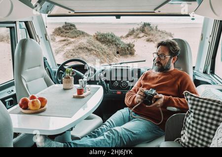 One man sitting and relaxing inside a camper van motor home dinette. Vanlife lifestyle and travel modern people. Holiday vacation with van for alterna Stock Photo