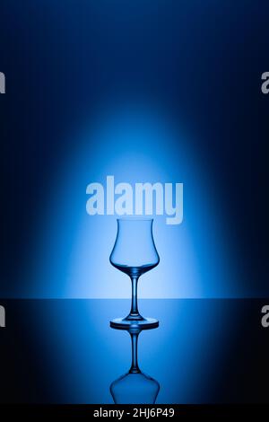 Rum tasting glass on the glass table and blue background Stock Photo