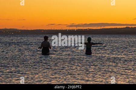 Portobello, Edinburgh, Scotland, UK. 27th January 2022. Mostly clear sky at sunrise with temperature of 7 degrees  centigrade for those out for exercise. Pictured: Makiko and friend enjoy a regular dawn dip in the Firth of Forth.  Credit: Archwhite/alamy live news Stock Photo