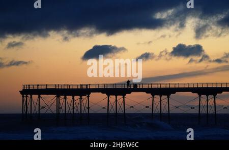 A person takes a picture of the sun rising over the North Sea from the pier at Saltburn in North Yorkshire. Picture date: Thursday January 27, 2022. Stock Photo