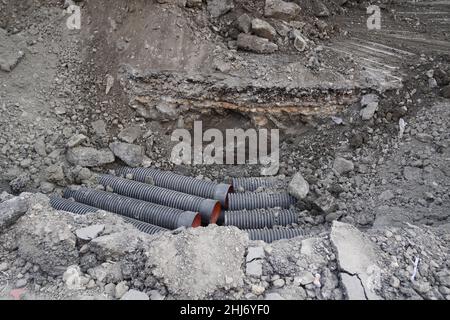 Ongoing construction works going on an Indian Street. Construction machine has dug up a trench in a road. Main street. Trench dug for an extension for Stock Photo
