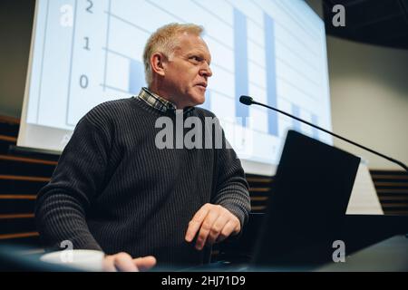 businessman speaking during a seminar. Senior male professional giving a speech in a summit. Stock Photo