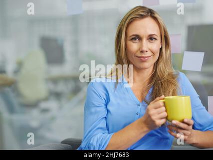I can't work without my coffee. Attractive blonde female employee having her coffee break. Stock Photo