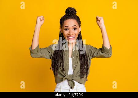 Photo portrait of excited woman cheering raising two fists up isolated on vivid yellow colored background Stock Photo