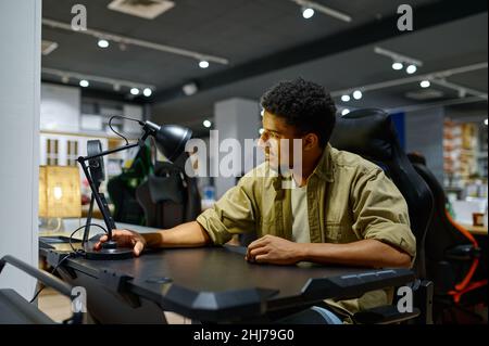 Man testing table lamp sitting at desk Stock Photo