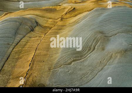 Wavy patterned layered sandstone in abstract patterns of grey and brown. Background texture Stock Photo