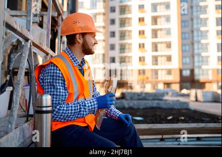 Construction worker eating sandwich during lunch break Stock Photo