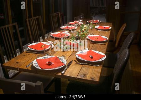 Family table from rustic wood with plates, red napkins and drinking glasses for a festive dinner with friends, selected focus, narrow depth of field Stock Photo