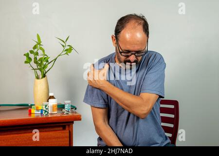 Senior man with shoulder pain. Middle-aged gentleman is in horrible pain. Neck and shoulder pain suffering from neck and shoulder injury, person with Stock Photo