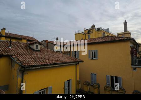 view of the red-tiled roofs of yellow houses and orange buildings in the town across the evening sky. City background. Italian architecture Stock Photo