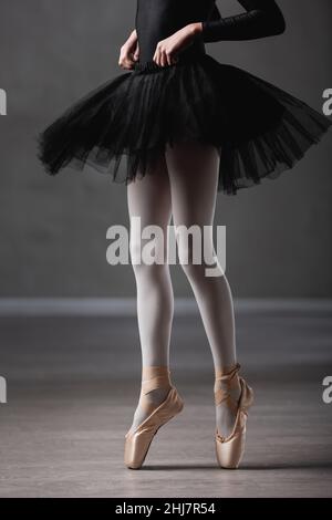 cropped view of girl in black tutu and pointe shoes dancing in ballet studio Stock Photo