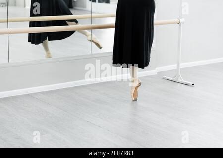 partial view of ballet dancer practicing at barre near mirrors Stock Photo
