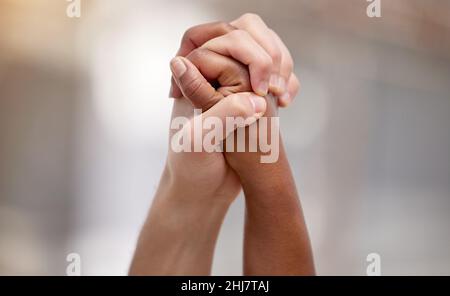 Bonded by a heartfelt cause. Shot of two people united and holding hands at a protest. Stock Photo