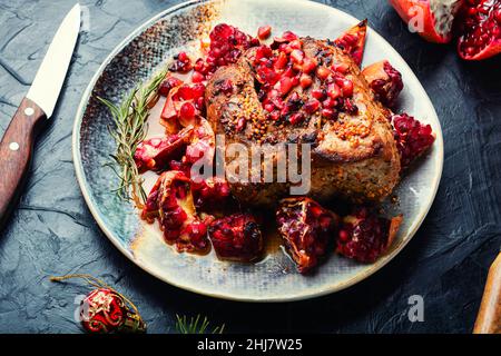 Appetizing piece of pork loin in a fruity marinade. Fried meat with pomegranate. Stock Photo