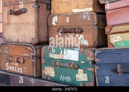 Close up of old battered luggage chests and suitcases stacked on trolley Stock Photo