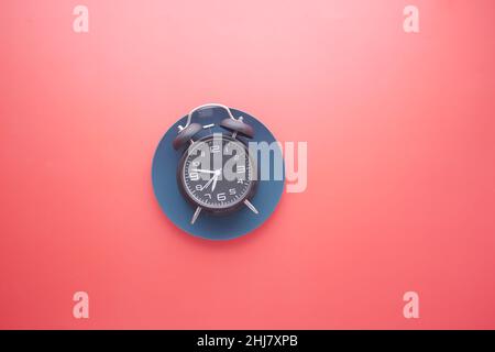 Alarm clock on plate on red background top down  Stock Photo