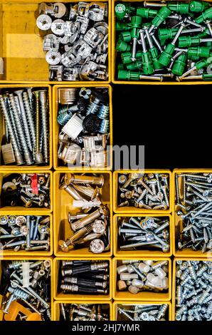 Yellow case with small construction objects. Many storage compartments filled with builders accessories Stock Photo