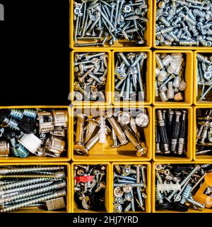 Yellow case with small construction objects. Many storage compartments filled with builders accessories Stock Photo