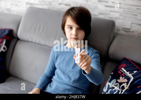 Child, preteen boy, holding home made covid 19 SWAB antigen test, home allowed tests, showing positive result Stock Photo
