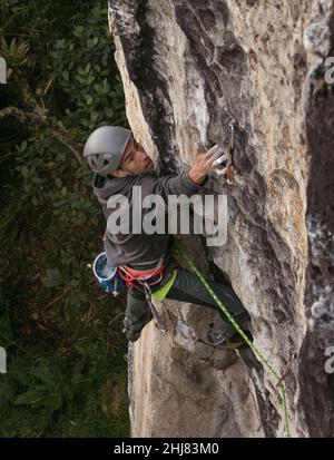 Candid shot of fit dark skinned male rock climber trying hard Stock Photo