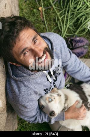 Hispanic man and brown border collie love each other outdoors Stock Photo