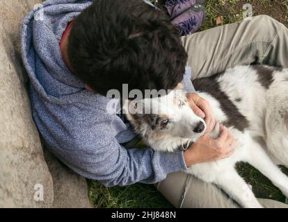 Hispanic man and brown border collie love each other outdoors Stock Photo