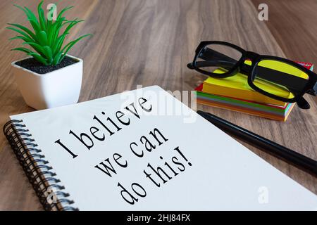 Motivational text on white notepad with potted plan, glasses, a pen and notes on wooden desk. Teamwork concept Stock Photo