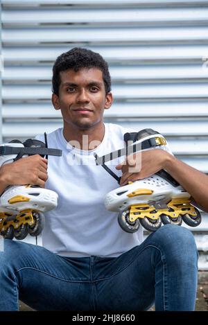 Portrait of confident young latino man wearing t-shirt and  inline skates. Stock Photo