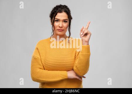 serious young woman pointing finger up Stock Photo