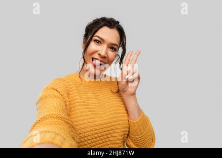 woman with pierced nose taking selfie shows peace Stock Photo