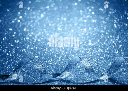 Christmas blue background with free place for text. Shiny serpentine ribbon on an abstract background with shining bokeh snowflakes. Stock Photo