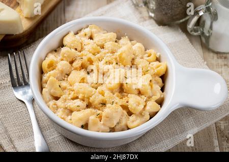 Macaroni and cheese sprinkled with parmesan in a white baking dish on a rustic wooden table Stock Photo