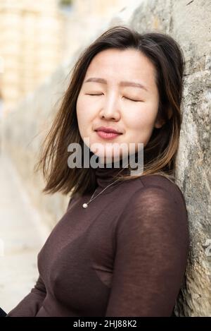 Portrait of an attractive 29 year old Asian American girl, standing eyes closed Stock Photo