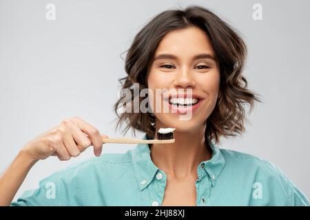 smiling woman with toothpaste on wooden toothbrush Stock Photo
