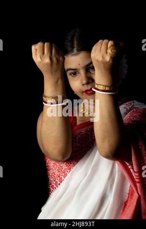 An Indian woman in red saree wearing bangles with smiling face on black background Stock Photo