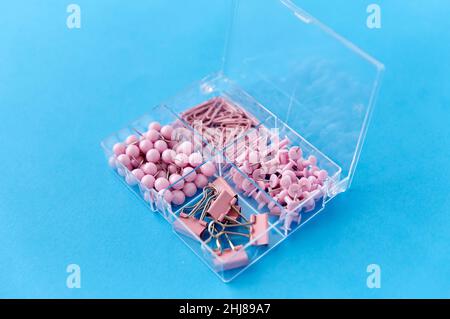 pins and clips in plastic pox on blue background Stock Photo